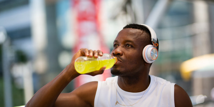 Man holding an energy drink can with a blurred couple in the background, illustrating energy drinks’ potential effects on sex drive.