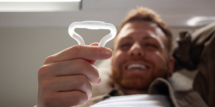 Man placing a silicone constriction ring at the base of his semi-erect penis to achieve a firmer, longer-lasting erection