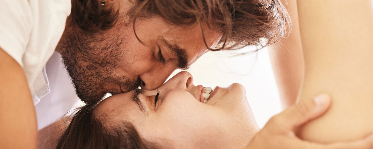 a man kissing his couple in her forehead while she smiles