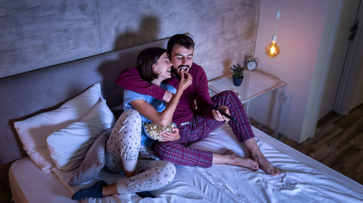 Happy couple watching a movie in bed
