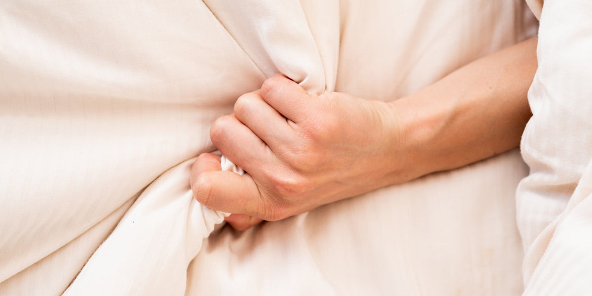Woman holding sheets tight because of sex pain