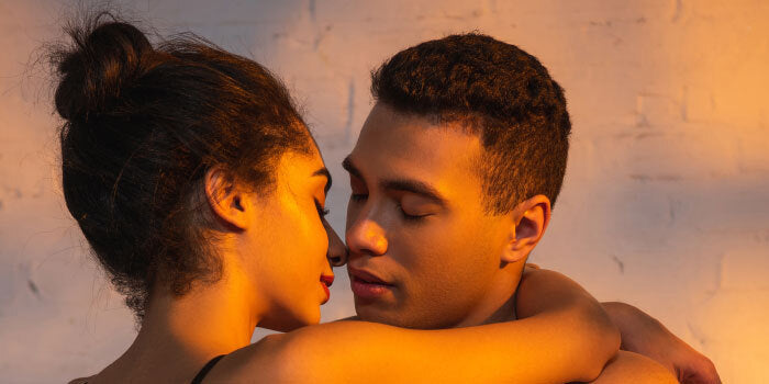 Man and partner seated face-to-face, eyes closed, synchronizing deep diaphragmatic breaths to improve ejaculation control and intimacy.