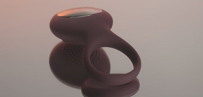 Close-up of a vibrating ring designed to enhance pleasure and prolong erections, placed on a smooth surface with soft lighting.