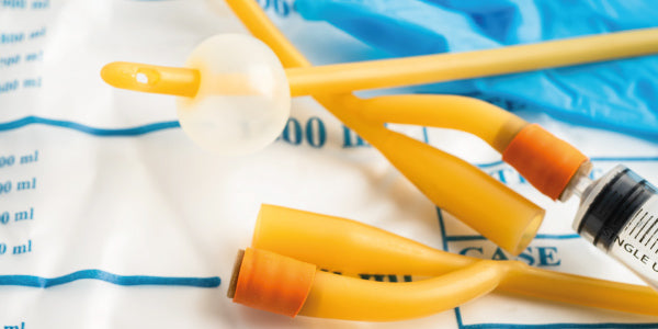 A healthcare professional preparing a urethral catheter for medical use.