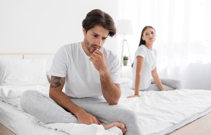 Couple holding hands in bed, comforting moment after a performance difficulty