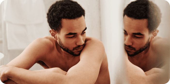 Man looking anxiously in mirror – illustration of male body dysmorphia