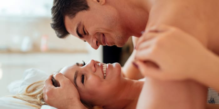 Couple hugging in bed during foreplay.