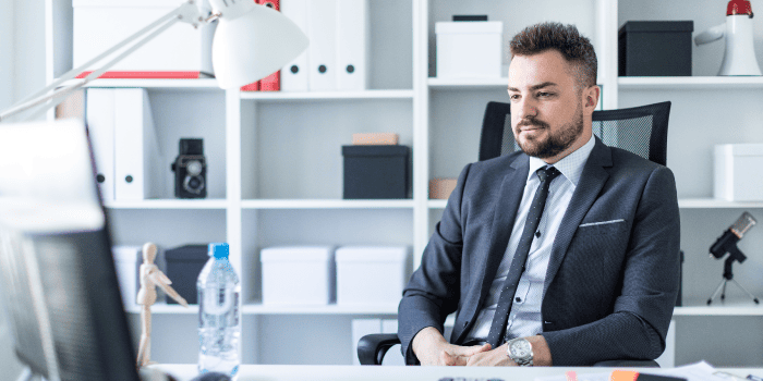 Young man stretching beside his office desk to boost blood flow and prevent erectile dysfunction caused by prolonged sitting.