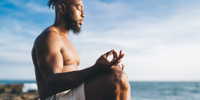Man and partner seated face-to-face, eyes closed, synchronizing deep diaphragmatic breaths to improve ejaculation control and intimacy.