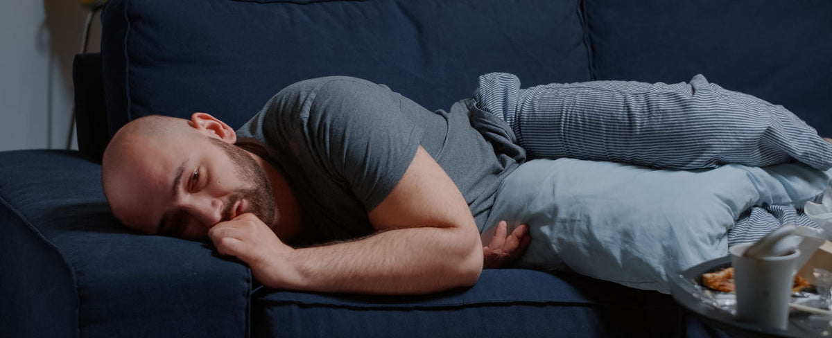 Man sitting thoughtfully on a bed, reflecting on sexual confidence after a difficult intimate experience