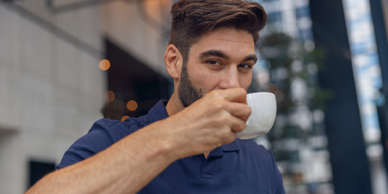Man holding a cup of coffee while reflecting on caffeine and male sexual health