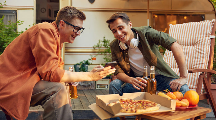 Male friends outdoors smiling and eating pizza