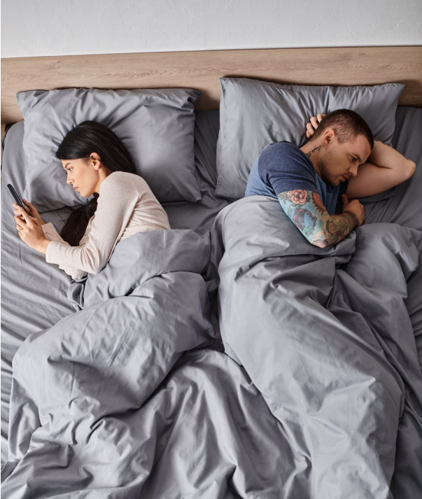 Couple in bed looking thoughtful, representing sexual monotony and the journey to rekindle passion and intimacy in long-term relationships.