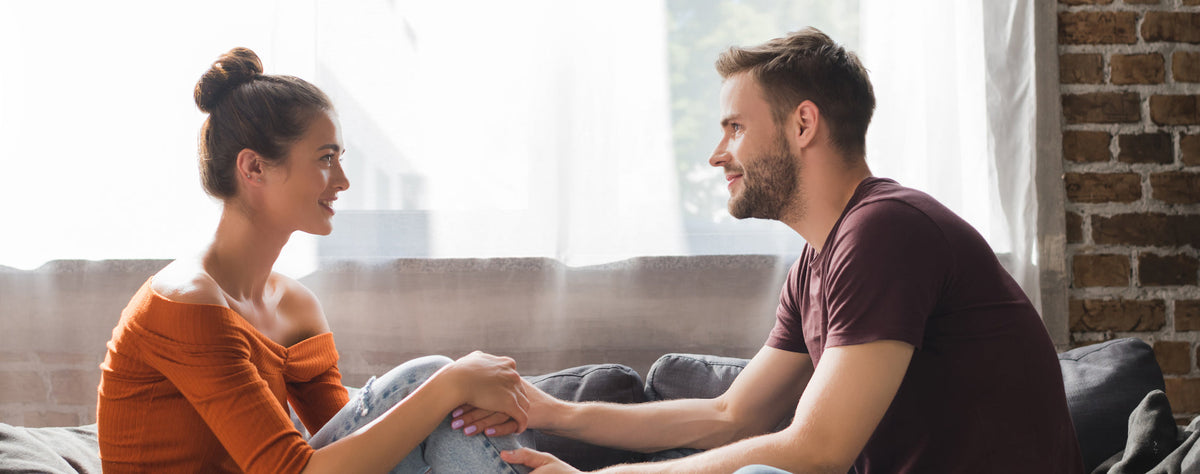 Couple calmly talking on a sofa practicing assertive communication to resolve a conflict