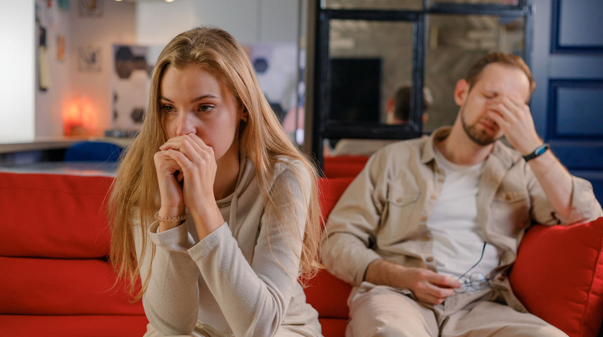 Couple sitting on a couch talking calmly in a warm, relaxed living room.