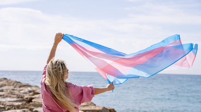 woman holding trans flag in the beach
