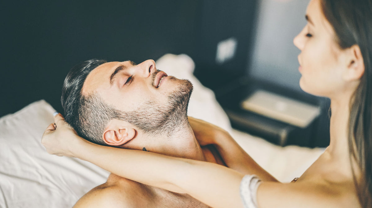 Man sitting fully clothed on his bed with eyes closed, practicing mindful breathing as part of a mindful masturbation routine to reduce performance anxiety.